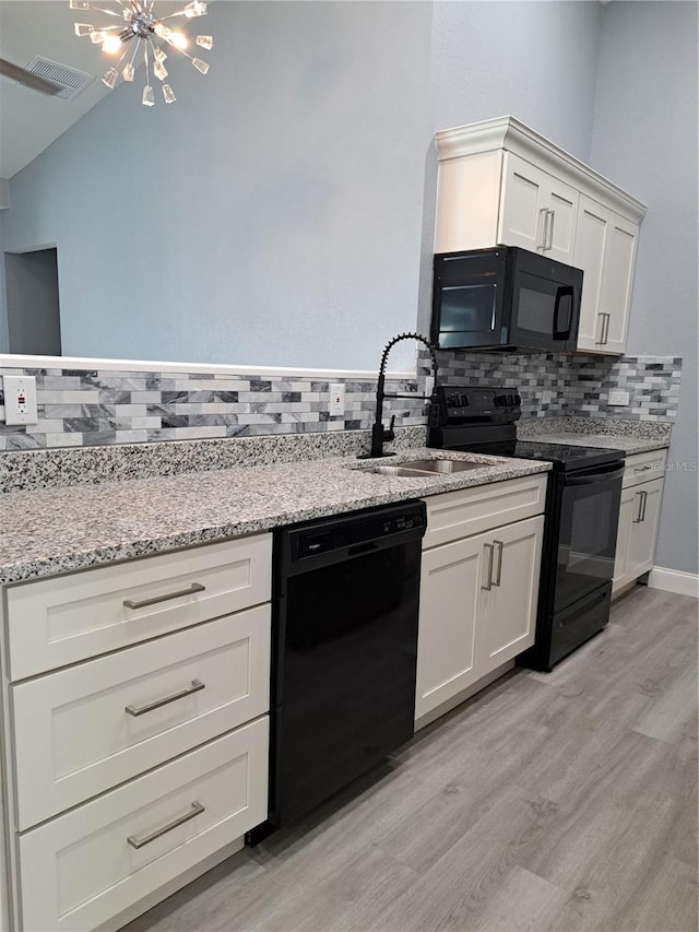26 Clintwood Ave, Englewood, FL 34223 - kitchen featuring black appliances, light wood-type flooring, tasteful backsplash, light stone countertops, and white cabinetry