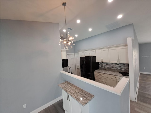 26 Clintwood Ave, Englewood, FL 34223 - kitchen with black fridge, a chandelier, wood finished floors, white cabinetry, and decorative backsplash