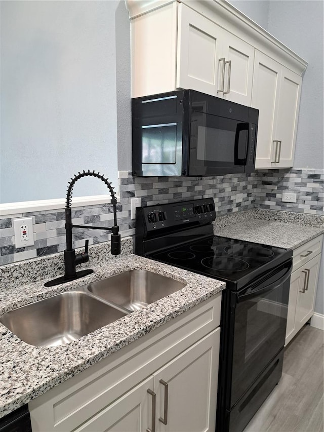 26 Clintwood Ave, Englewood, FL 34223 - kitchen with black appliances, decorative backsplash, white cabinetry, and light wood-type flooring