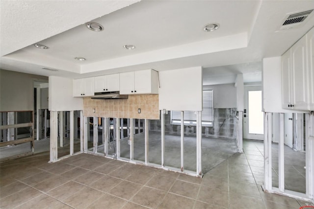 104 Carlyle Cir, Palm Harbor, FL 34683 - kitchen with a raised ceiling, under cabinet range hood, light tile patterned flooring, white cabinets, and tasteful backsplash