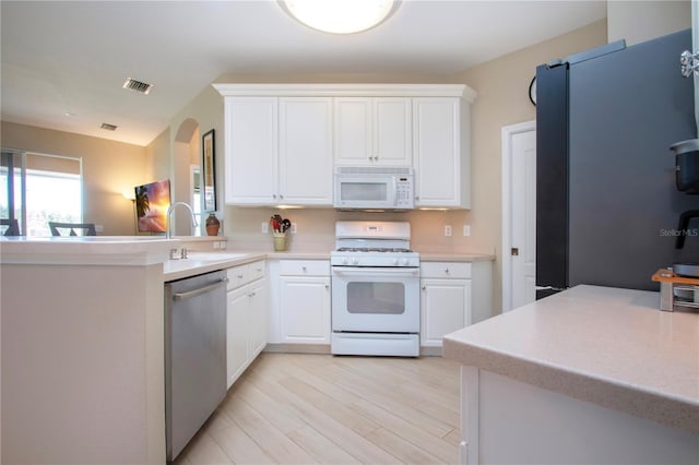 kitchen with white cabinetry, light countertops, white appliances, a sink, and visible vents