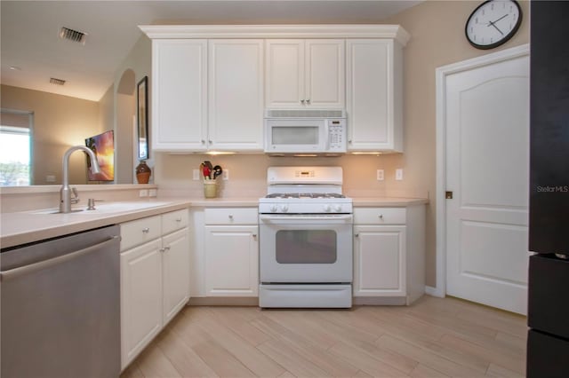 kitchen with light countertops, visible vents, white cabinets, white appliances, and a sink
