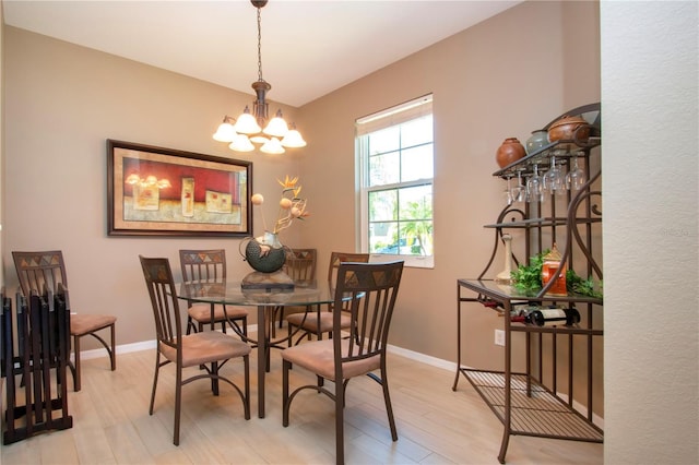 dining room featuring an inviting chandelier, baseboards, and light wood finished floors
