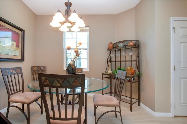 dining area with baseboards, light wood-style flooring, and a notable chandelier