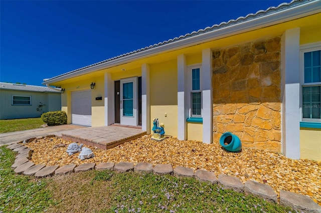 5427 Springwood Blvd Unit 5427, Pinellas Park, FL 33782 - doorway to property featuring a garage, stucco siding, driveway, and stone siding