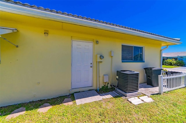 5427 Springwood Blvd Unit 5427, Pinellas Park, FL 33782 - view of exterior entry with central AC unit, stucco siding, a yard, and fence