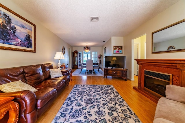 5427 Springwood Blvd Unit 5427, Pinellas Park, FL 33782 - living area featuring a glass covered fireplace, light wood finished floors, a textured ceiling, and visible vents