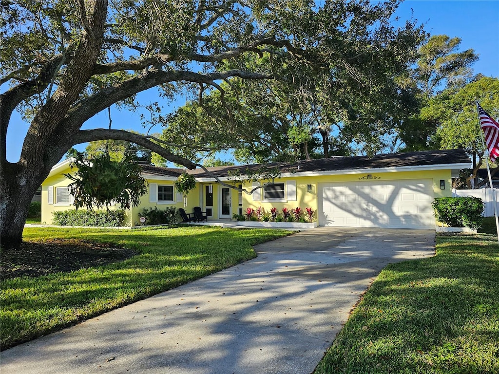 ranch-style home with concrete driveway, a garage, a front lawn, and stucco siding