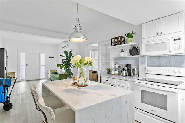 819 11th St N, Saint Petersburg, FL 33705 - kitchen featuring white appliances, light stone countertops, a kitchen island, white cabinets, and light wood-type flooring