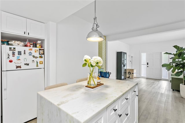 819 11th St N, Saint Petersburg, FL 33705 - kitchen featuring light wood-type flooring, light stone counters, a center island, white cabinetry, and freestanding refrigerator