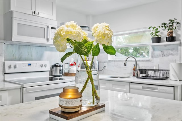 819 11th St N, Saint Petersburg, FL 33705 - kitchen with light stone countertops, decorative backsplash, white appliances, white cabinetry, and a sink