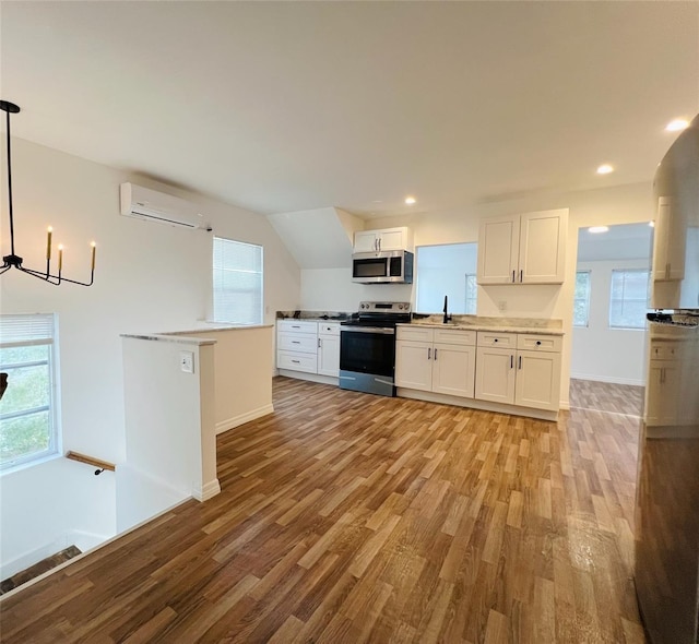 819 11th St N, Saint Petersburg, FL 33705 - kitchen featuring stainless steel appliances, a notable chandelier, light wood-style flooring, and a wall mounted AC