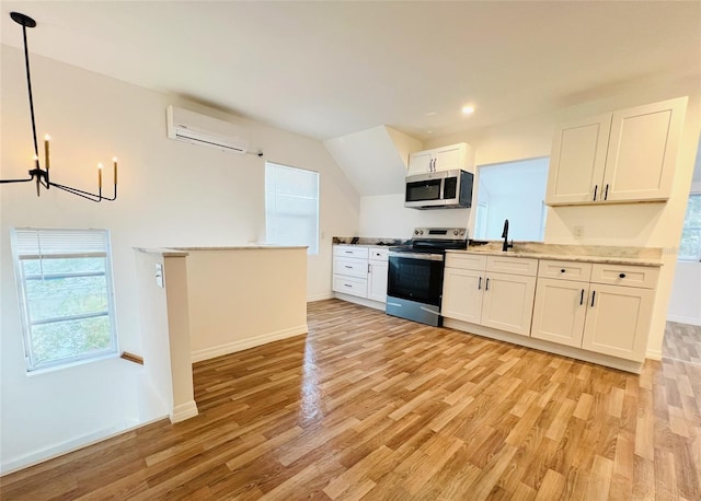 819 11th St N, Saint Petersburg, FL 33705 - kitchen featuring a wall unit AC, light wood-style flooring, appliances with stainless steel finishes, a notable chandelier, and white cabinets