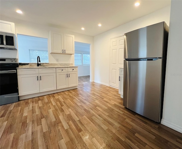 819 11th St N, Saint Petersburg, FL 33705 - kitchen featuring light wood finished floors, baseboards, recessed lighting, stainless steel appliances, and white cabinetry