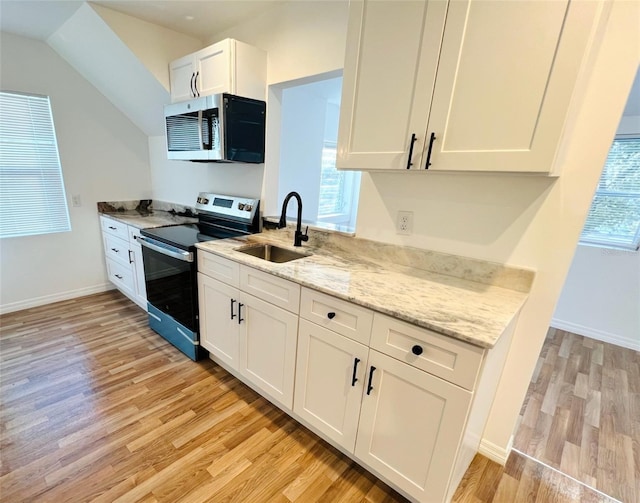 819 11th St N, Saint Petersburg, FL 33705 - kitchen with a sink, white cabinets, light wood-type flooring, and stainless steel appliances