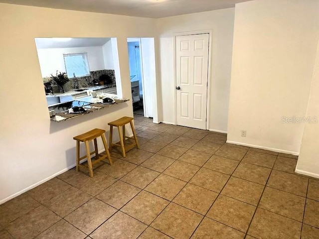 819 11th St N, Saint Petersburg, FL 33705 - kitchen with a breakfast bar, tile patterned floors, baseboards, and backsplash
