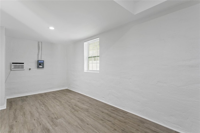 819 11th St N, Saint Petersburg, FL 33705 - empty room featuring an AC wall unit, electric panel, wood finished floors, and recessed lighting