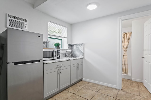 819 11th St N, Saint Petersburg, FL 33705 - kitchen with baseboards, a sink, gray cabinetry, an AC wall unit, and appliances with stainless steel finishes