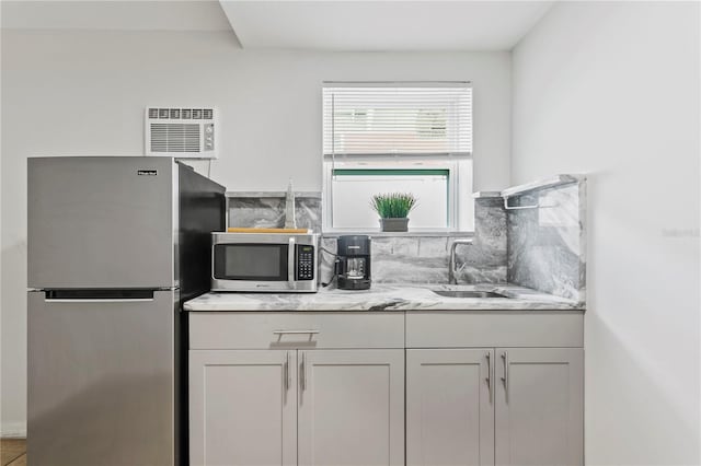 819 11th St N, Saint Petersburg, FL 33705 - kitchen with a sink, light stone counters, backsplash, white cabinetry, and stainless steel appliances