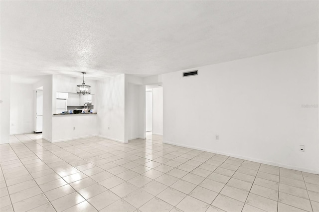 2650 Countryside Blvd Unit B102, Clearwater, FL 33761 - unfurnished living room featuring a textured ceiling, baseboards, visible vents, light tile patterned flooring, and a chandelier
