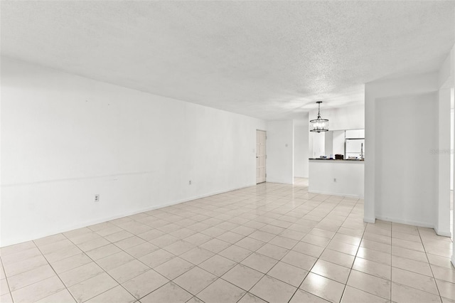 2650 Countryside Blvd Unit B102, Clearwater, FL 33761 - unfurnished living room featuring a textured ceiling, light tile patterned flooring, a notable chandelier, and baseboards