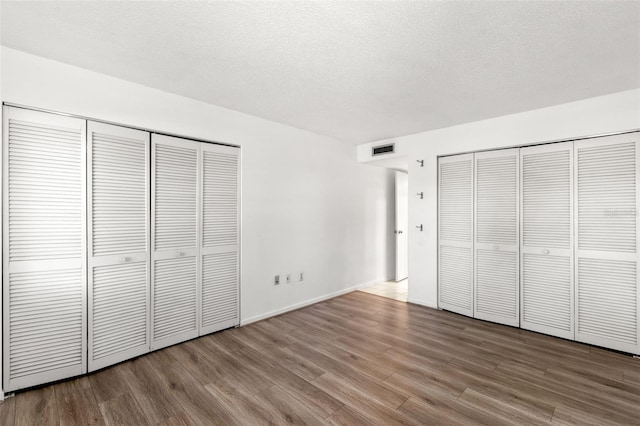 2650 Countryside Blvd Unit B102, Clearwater, FL 33761 - unfurnished bedroom featuring multiple closets, visible vents, a textured ceiling, and wood finished floors