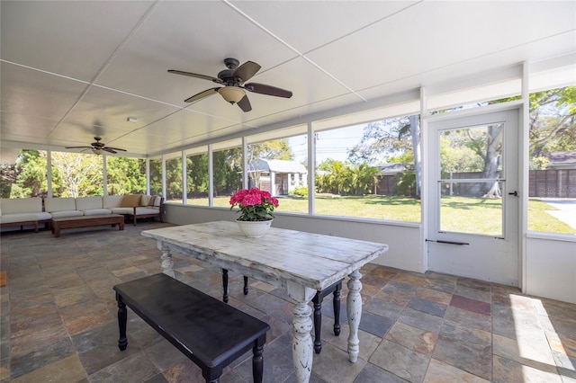 sunroom featuring outdoor dining area, ceiling fan, and an outdoor hangout area