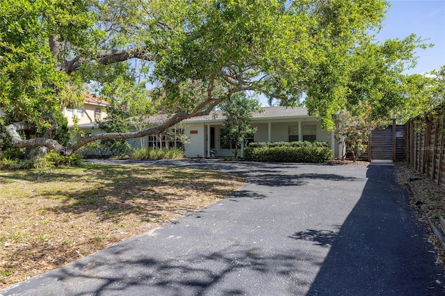 view of front of property with fence, covered porch, stucco siding, and driveway