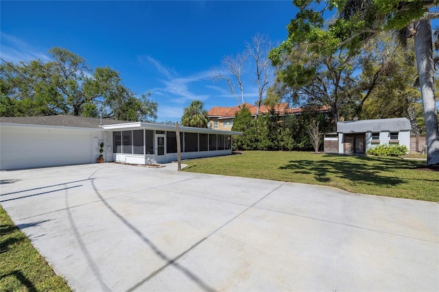 view of patio with driveway, an outbuilding, a sunroom, and a garage