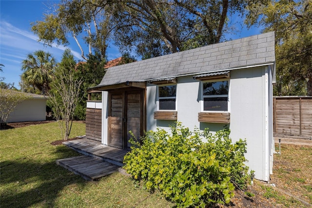 view of outdoor structure with fence and an outbuilding