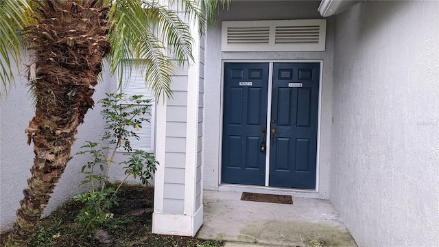 entrance to property with visible vents and stucco siding