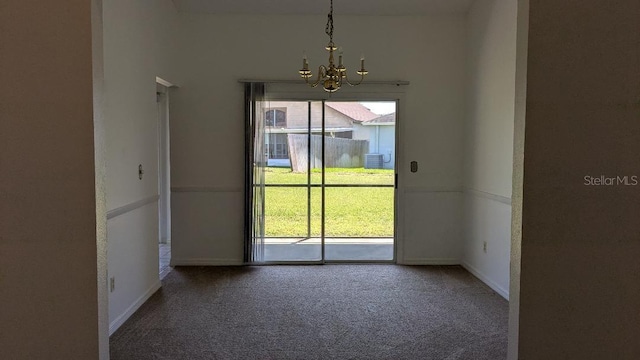 carpeted spare room with a notable chandelier, a healthy amount of sunlight, and baseboards