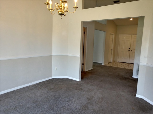 carpeted spare room featuring visible vents, baseboards, and a chandelier