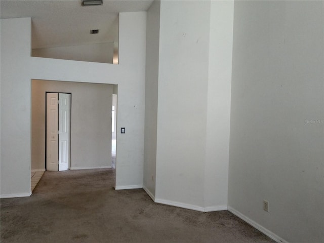 unfurnished room featuring high vaulted ceiling, visible vents, baseboards, and carpet