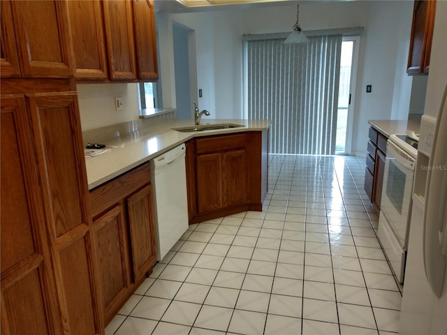 kitchen featuring a sink, white appliances, brown cabinetry, and light countertops