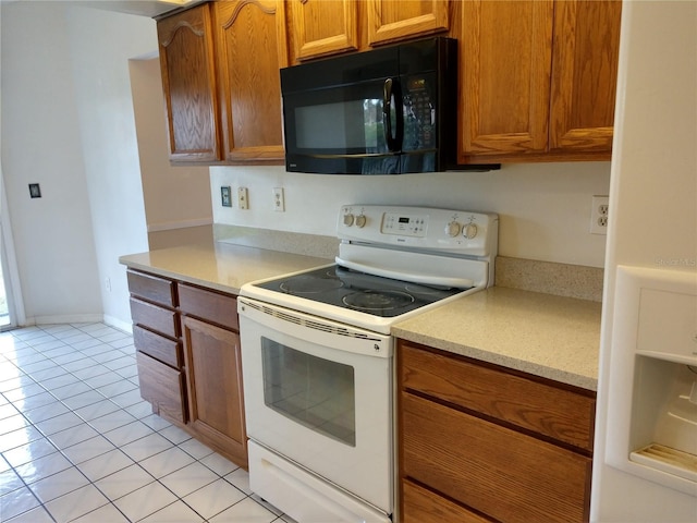 kitchen featuring electric stove, light tile patterned flooring, brown cabinetry, light countertops, and black microwave