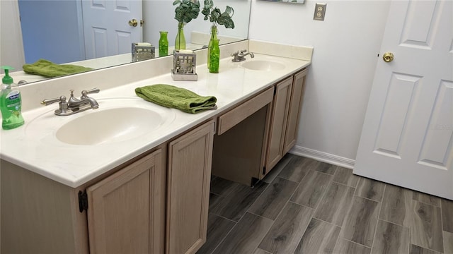 full bathroom featuring double vanity, wood tiled floor, baseboards, and a sink