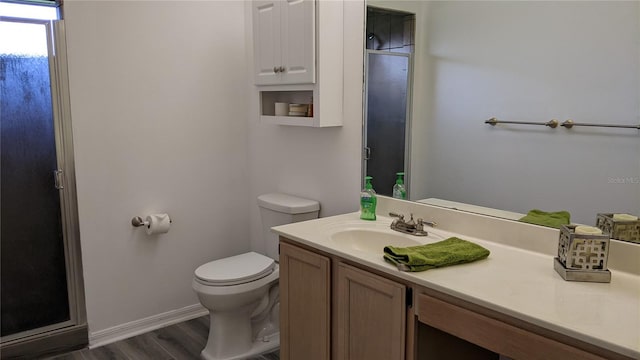 full bath with a shower with shower door, toilet, wood finished floors, baseboards, and vanity