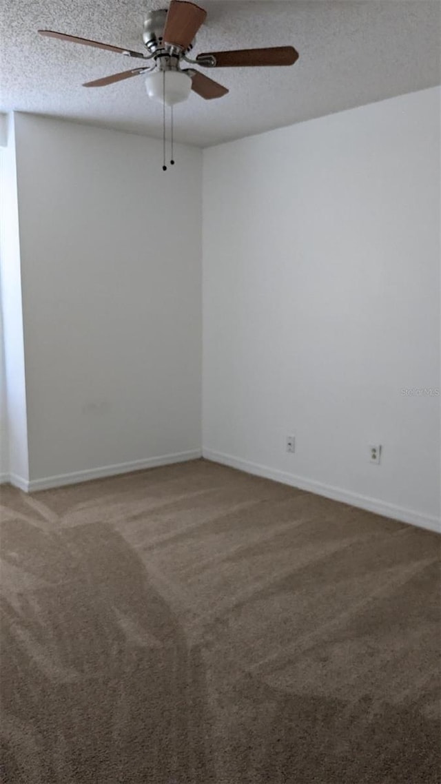 carpeted empty room with baseboards, a textured ceiling, and a ceiling fan