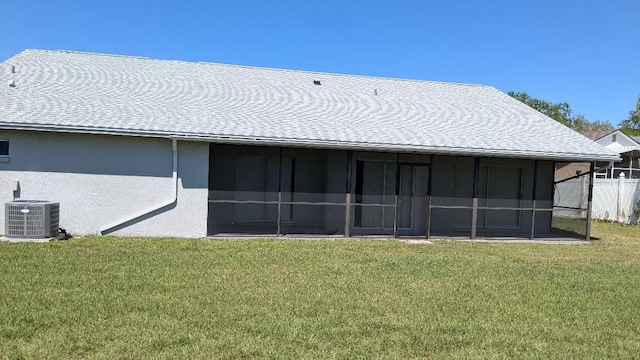 rear view of property with a yard, central AC, stucco siding, and a sunroom