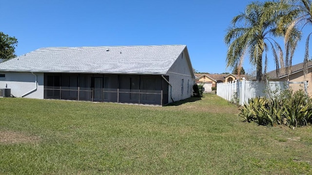 rear view of house featuring stucco siding, a yard, and a sunroom