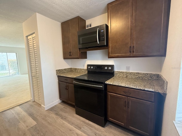 7529 Pitch Pine Cir Unit 190, Tampa, FL 33617 - kitchen with stainless steel microwave, dark brown cabinets, black range with electric cooktop, and light wood finished floors