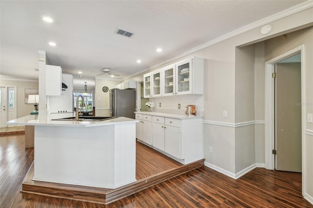 kitchen with freestanding refrigerator, ornamental molding, white cabinets, dark wood-style flooring, and a sink