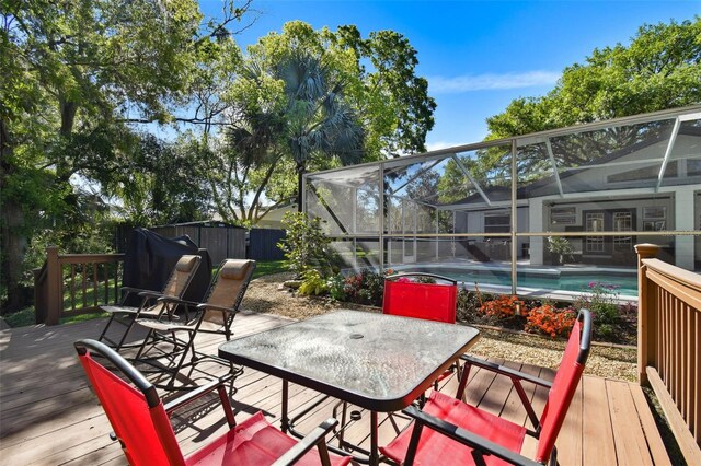wooden deck featuring outdoor dining space, a fenced in pool, and a lanai
