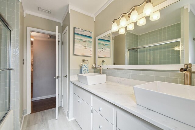 full bathroom featuring a sink, a tile shower, wood finished floors, and crown molding