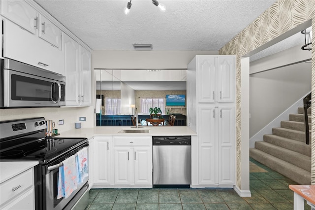 6140 Sun Blvd Unit 7, Saint Petersburg, FL 33715 - kitchen featuring appliances with stainless steel finishes, light countertops, white cabinets, and a textured ceiling
