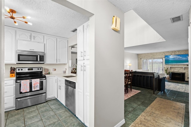 6140 Sun Blvd Unit 7, Saint Petersburg, FL 33715 - kitchen featuring stainless steel appliances, a textured ceiling, white cabinetry, light countertops, and open floor plan