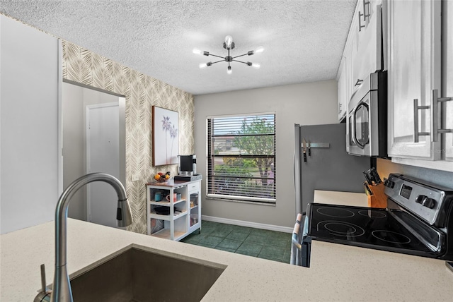 6140 Sun Blvd Unit 7, Saint Petersburg, FL 33715 - kitchen with appliances with stainless steel finishes, a chandelier, wallpapered walls, white cabinets, and a textured ceiling