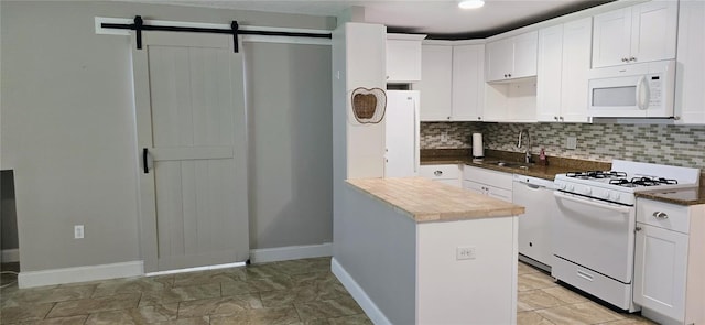 5725 80th St N Unit 107, Saint Petersburg, FL 33709 - kitchen with white appliances, decorative backsplash, white cabinets, a barn door, and dark countertops