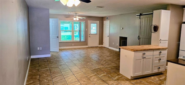 5725 80th St N Unit 107, Saint Petersburg, FL 33709 - kitchen featuring a ceiling fan, white cabinetry, a barn door, light marble finish flooring, and a textured ceiling